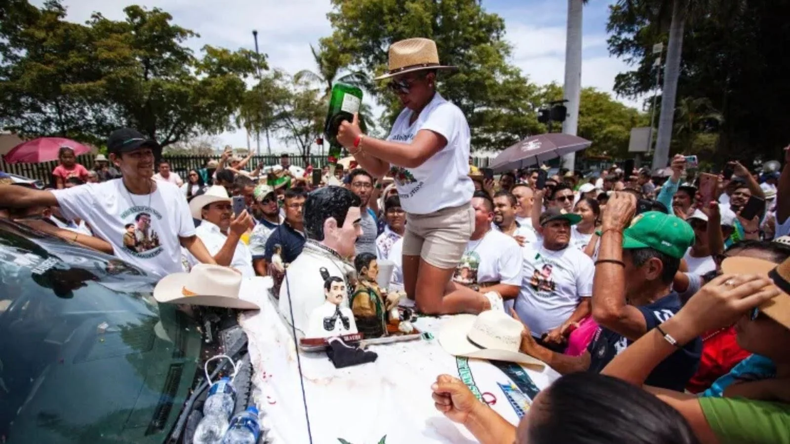 Pessoas jogando bebidas em cima de uma imagem do santo durante procissão. Imagem: Uol.